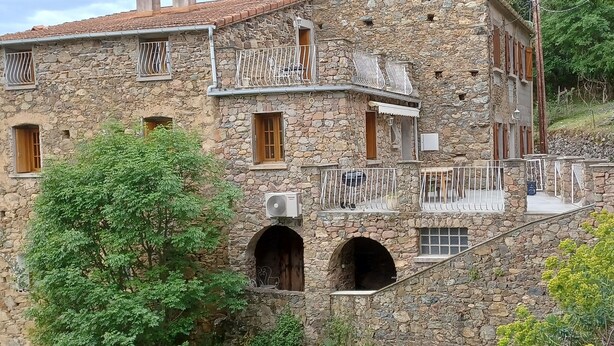 A stone building with multiple balconies, arched doorways, and a staircase.