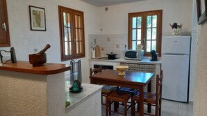 A kitchen with wooden cabinets, a microwave, a refrigerator, and a dining table with chairs.
