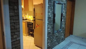 Un corridoio stretto che conduce a una cucina con frigorifero e forno a microonde.