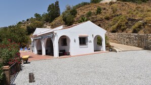Un edificio blanco con arcos, un camino de grava y un muro de piedra.