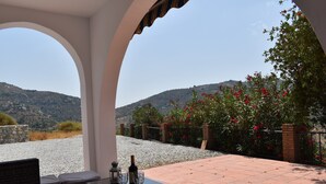 Un patio con una mesa preparada para dos, con vistas a un paisaje montañoso.