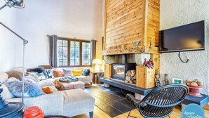 Una sala de estar acogedora con chimenea, un conjunto de sofá, un televisor y una pared de madera.