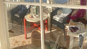A room with a large window overlooking a body of water, furnished with a table, chairs, and a basket. - Seaside century house with beautiful sunset and big jetty with sauna  (ljusterö)