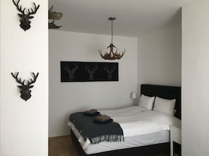 Une chambre à coucher avec un lit, un lustre et des bois de cerf accrochés au mur.