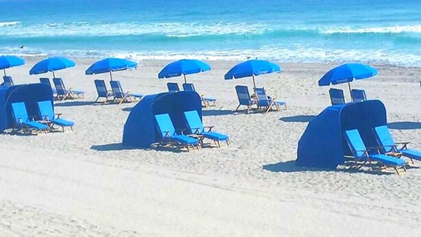 Una platja amb files de gandules blaves i ombrel·les.