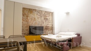 Un dormitorio moderno con cama, televisor, escritorio y silla.