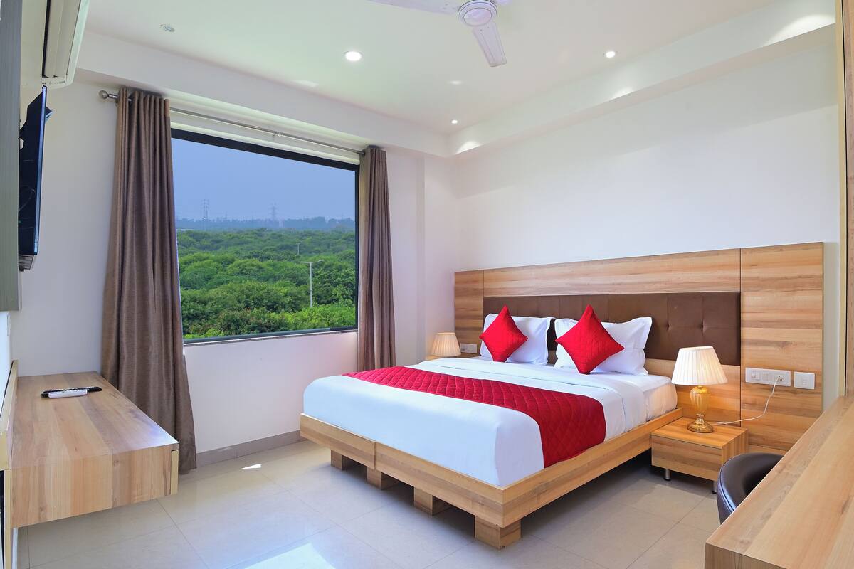 Een moderne hotelkamer met een groot bed, een houten hoofdeinde en een bureau met stoel.
