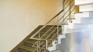 A modern staircase with metal railings and a granite floor. - MY HOTEL (New Delhi)