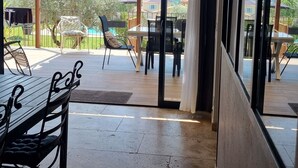 A spacious balcony with a table and chairs, large windows offering a view of the outdoors, and a ceiling light fixture. - Spacious VILLA 286 m2 overlooking the Sainte Victoire, garden, swimming pool. (Pertuis)