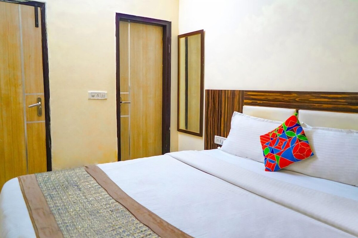 Une chambre d’hôtel avec un lit, une tête de lit en bois, un miroir et une porte.