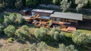 A modern house with a large deck, outdoor seating, and a stone wall.
