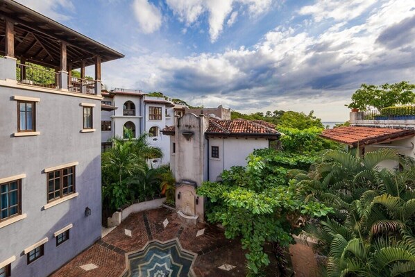 A courtyard with a pool, surrounded by buildings with a mix of modern and traditional architecture, including a balcony and a covered area.
