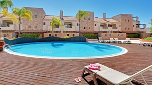 A swimming pool with lounge chairs and a wooden deck. - VICTORIA SECRET APARTMENT (Vilamoura)