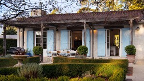 A rustic house with a covered patio, open blue shutters, and a garden with hedges and potted plants. - The French House-Luxury Country Retreat (Trentham)