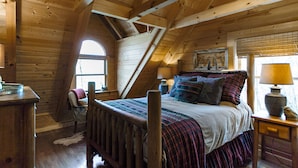 Une chambre mansardée chaleureuse, avec un plafond en pente, un lit en bois, une chaise, un bureau et une fenêtre.