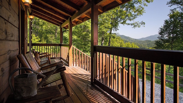 Une terrasse en bois avec une rambarde, des bancs et un seau en métal.