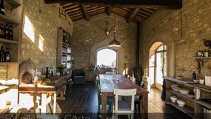 A rustic kitchen with stone walls, wooden beams, and a large wooden table. - SanMartino Apartmento - Sun, pool, sea (Cafaggio)