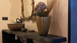 A bathroom vanity with a large mirror, a vase with flowers, and a sink. - SanMartino Apartmento - Sun, pool, sea (Cafaggio)