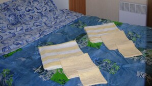Un dormitorio con cama, mesita de noche, lámpara, ventana con cortinas y radiador.