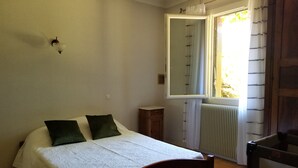 Quarto com cama de madeira, mesa de cabeceira, espelho e radiador.