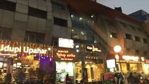 Un edificio de varios pisos con letreros iluminados que dicen 'Jdupi Upahar' y 'Mahap Ashta'.