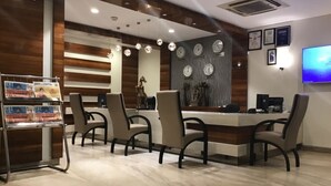 Una sala de conferencias moderna con una mesa larga, cuatro sillas, un mostrador de recepción y un televisor montado.