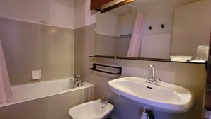 Un baño con bañera, lavabo y espejo.