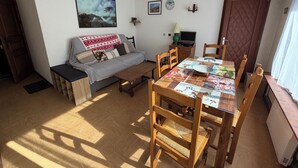 Una sala acogedora con un sofá, una mesa de comedor con sillas, un televisor y una puerta.