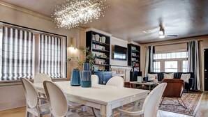 Un comedor con una mesa y sillas blancas, rodeado de estanterías y una chimenea.
