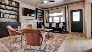 Una sala de estar con chimenea, un sofá, una mesa de centro y una estantería.