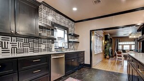 Una cocina moderna con armarios negros, un salpicadero con estampado y un suelo de baldosas hexagonales.