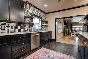 Une cuisine moderne avec des meubles de rangement noirs, un pare-feu décoré et un sol carrelé avec des motifs hexagonaux.