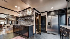 Una cocina moderna con una isla central, muebles oscuros y un refrigerador de acero inoxidable.