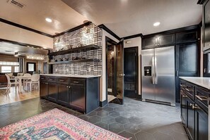 Une cuisine moderne dotée d’un îlot central, de meubles de couleur sombre et d’un réfrigérateur en acier inoxydable.