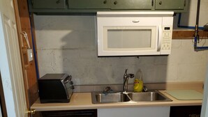 A compact kitchen with a microwave, toaster, sink, and dishwasher. - Basement Studio Apartment (Sanborn)