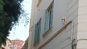 A building with a staircase leading up to a door, a green fence, and a sign with a logo. - 3min walk BEACHES, PARKING Town Hall, Pedestrian street Quiet 42 m2 CLIM 3p max (Menton)