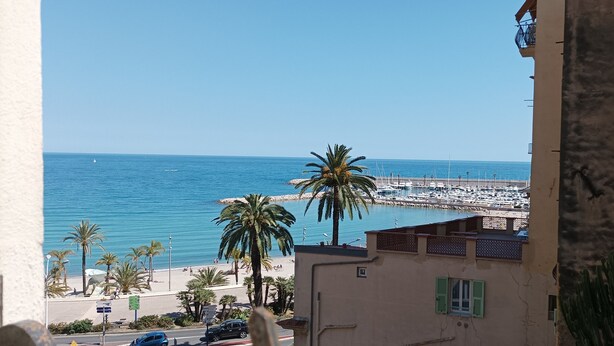 A coastal view with a marina, palm trees, and a building with a balcony. - 3min walk BEACHES, PARKING Town Hall, Pedestrian street Quiet 42 m2 CLIM 3p max (Menton)