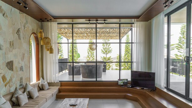 A modern living room with a stone wall, a sofa, a coffee table, and a TV. - Sunshine City View Villa 6BR wth a private Heated Pool (Cimenyan)