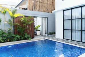 A modern pool area with a clear blue pool, surrounded by lush greenery and a wooden fence. - Sunshine City View Villa 6BR wth a private Heated Pool (Cimenyan)