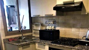 A compact kitchen with a sink, stove, oven, and microwave. - Luxurious modern apartment Coralia Marrakech for rent (Marrakech)