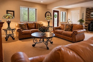 A living room with two brown leather sofas, a round coffee table, and two side tables with lamps.