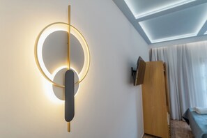 A modern room with a circular light fixture, a wooden door, and a bed with a blue cover.