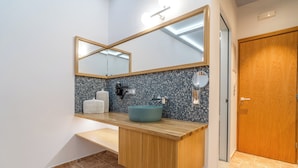 Een badkamer met een houten wastafelmeubel, een blauwe wastafel, een spiegel en een handdoekrek.