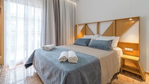 Een moderne hotelkamer met een groot bed, een houten hoofdbord en een nachtkastje met een lamp.