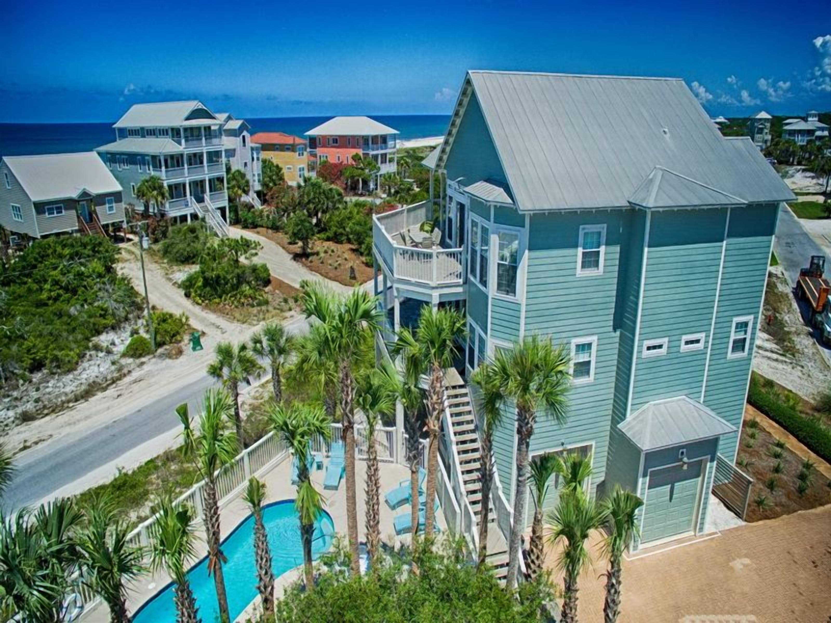 A coastal residential area with multiple two-story houses, a swimming pool, and a view of the ocean.