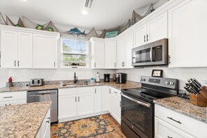 A kitchen with white cabinets, a stainless steel microwave, a black oven, and a granite countertop.