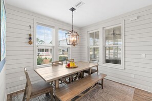 A dining area with a wooden table, benches, and a hanging light fixture.