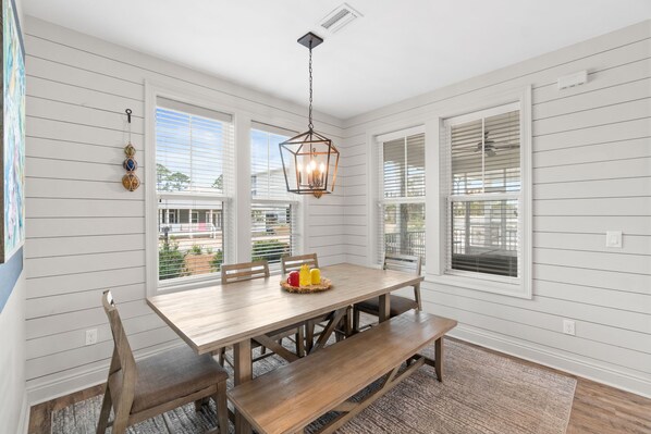 A dining area with a wooden table, benches, and a hanging light fixture.