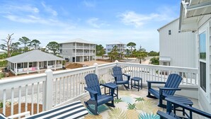 A balcony with Adirondack chairs, a patterned floor, and a view of other buildings and trees. - (4 Minute Walk to Beach) Screened in porch & MBR  on ground level (Cape San Blas)