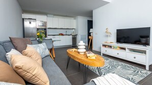 A modern living room with a grey sofa, a wooden coffee table, and a flat-screen TV. - Cozy apartment with pool (CN)